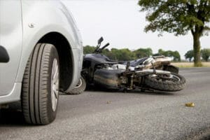 A car in front of a wrecked motorcycle