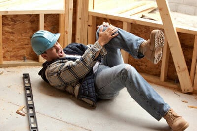 A construction worker lays on the ground in obvious pain