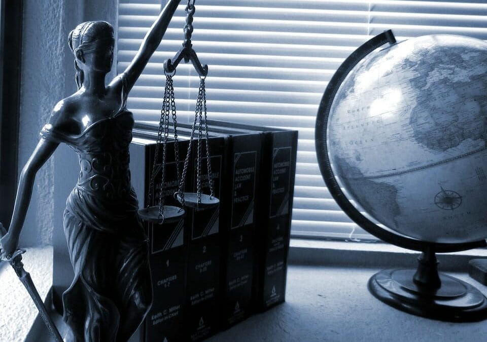 Lady Justice on a desk beside law books and a globe.