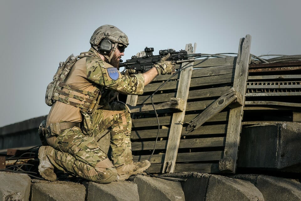 A military member aiming down range whioe wearing the defective earplugs.