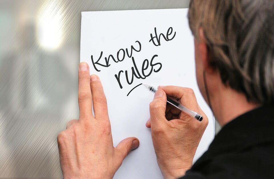 A man writing on paper the words "Know the Rules"