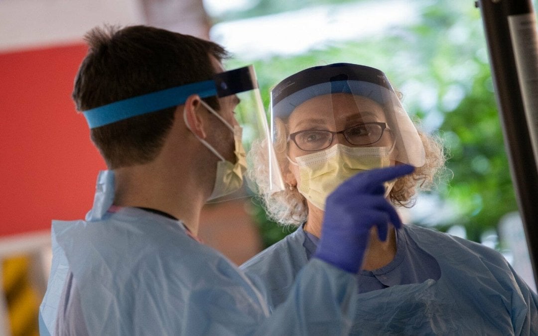Two healthcare workers with face shields, masks and other PPE during the COVID-19 outbreak.